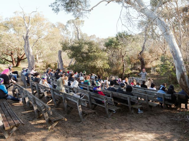 Campers gathered on bush benches under gum trees
