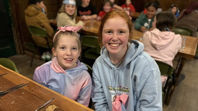 Two campers smiling at a meal table in the camp dining hall