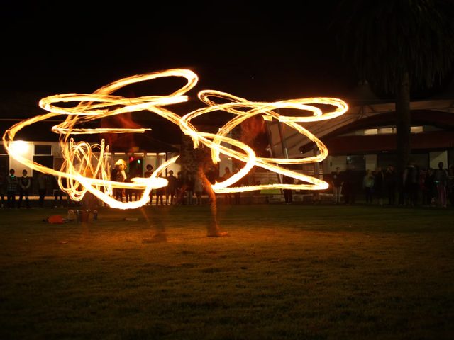 Fire-twirling performance at night while campers watch from a distance