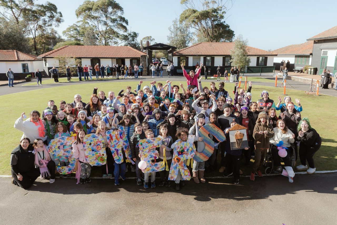 The whole Somers Camp group cheering and holding letters spelling the camp name