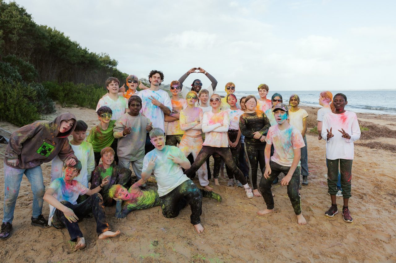 Somers campers covered in colourful powder, laughing together on the beach