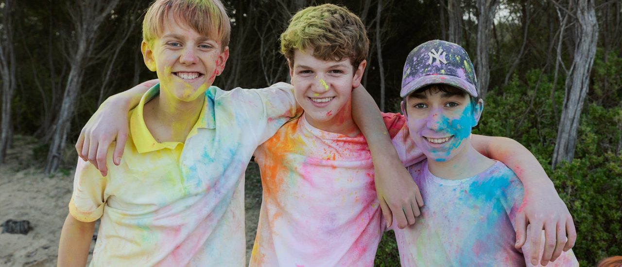 Three campers covered in colour powder, arms around each other, grinning