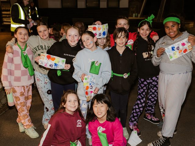 Campers in pyjamas at night holding their colourful activity sheets