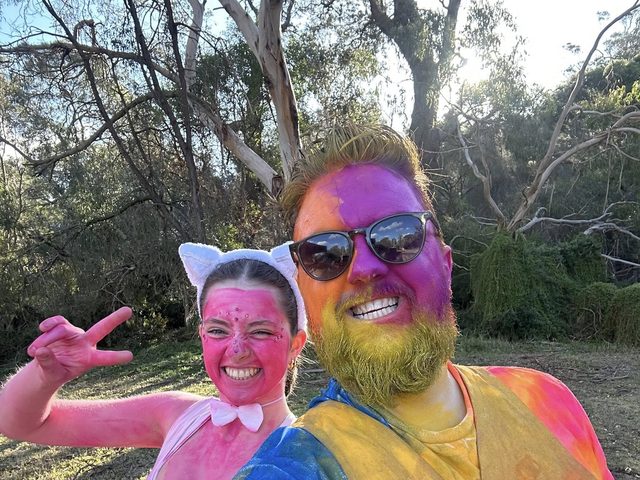 Two leaders covered in colourful powder, laughing and pulling silly poses